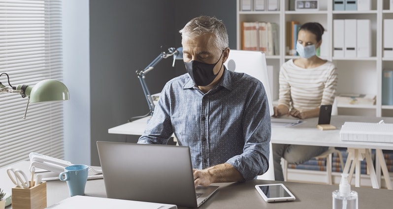 Coronavirus prevention and social distancing in the office: business people keeping safety distance and wearing a face mask, coronavirus prevention concept